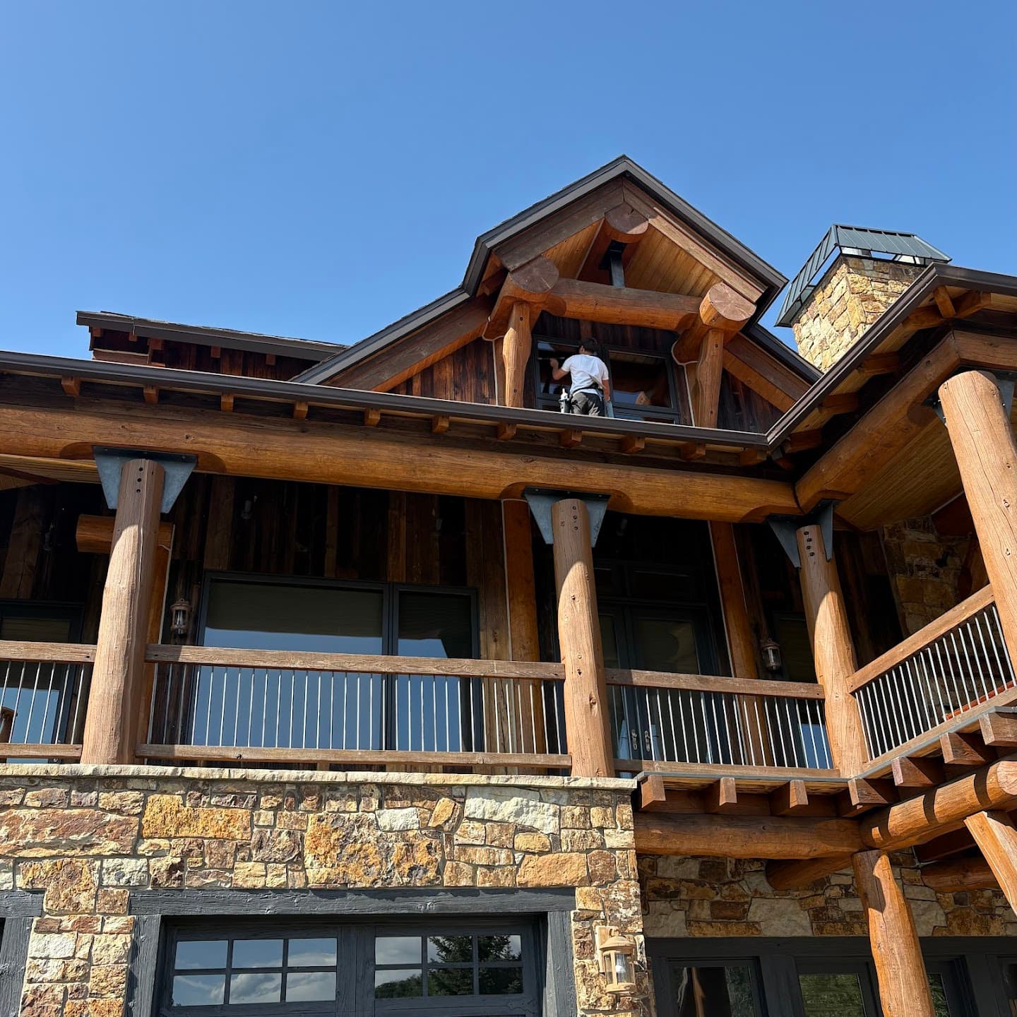 Lumen technician cleaning windows on a luxury log cabin in Steamboat Springs
