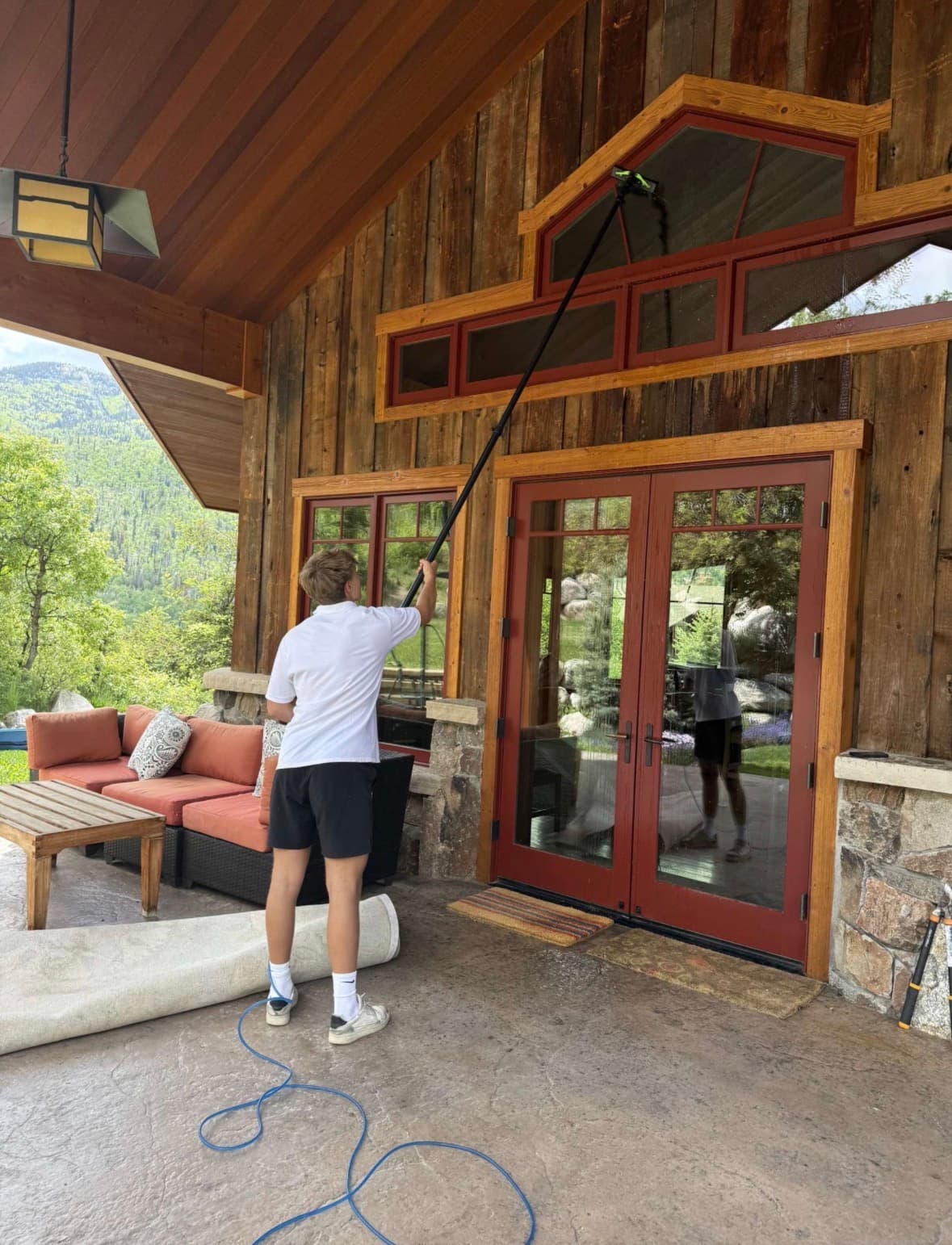 Lumen technician cleaning windows on a rustic Colorado mountain home